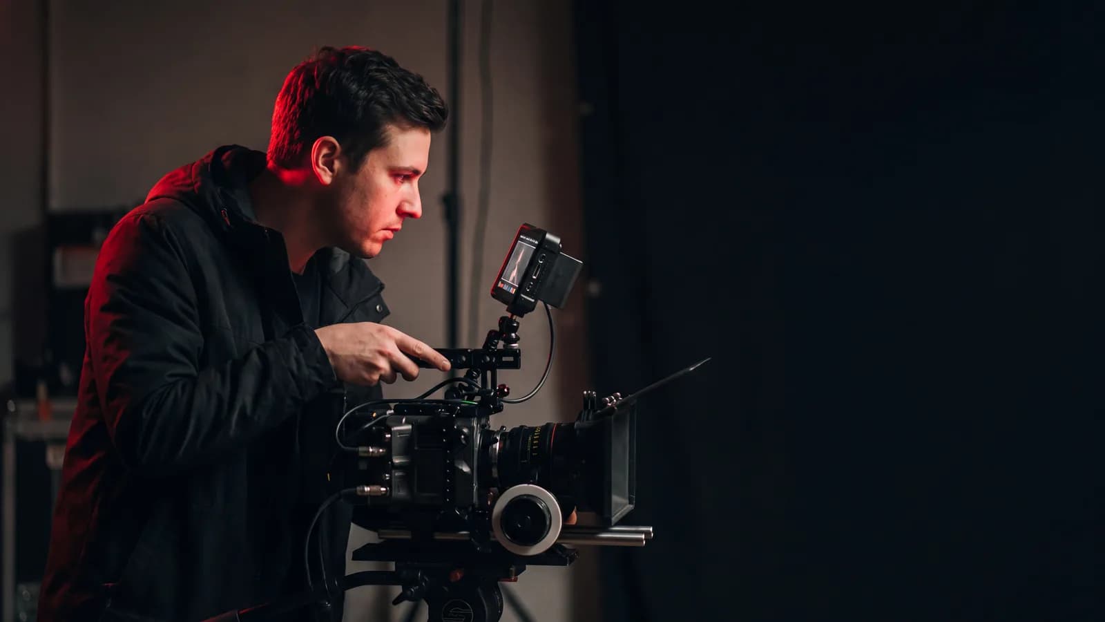 A content producer checking a cinema camera monitor on a darkened set