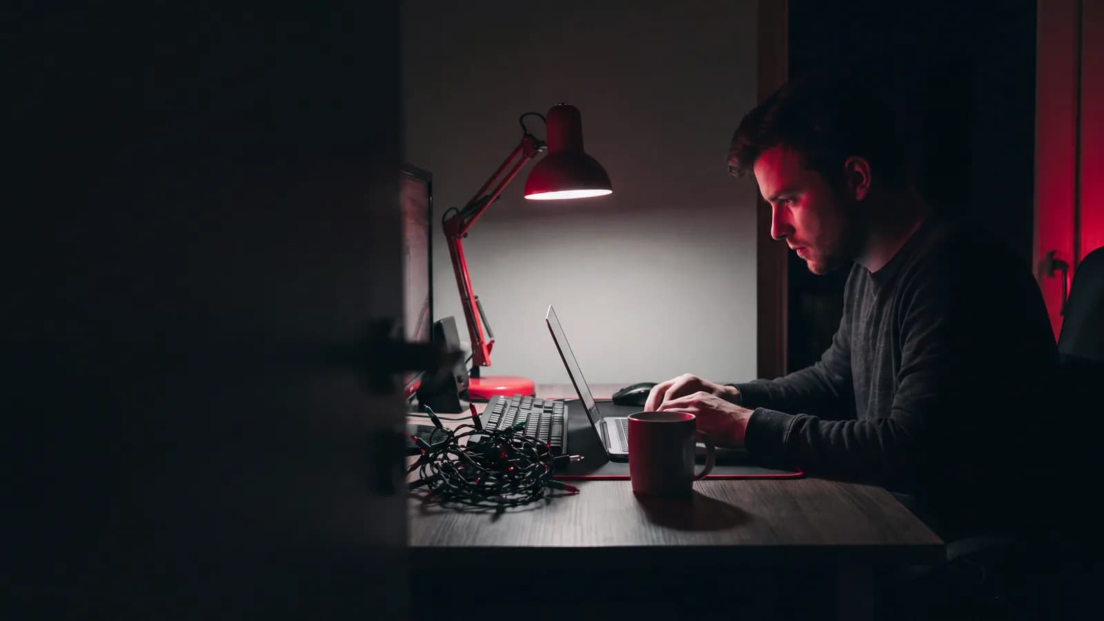 An email marketer working late, a coiled string of festive bulbs beside the keyboard